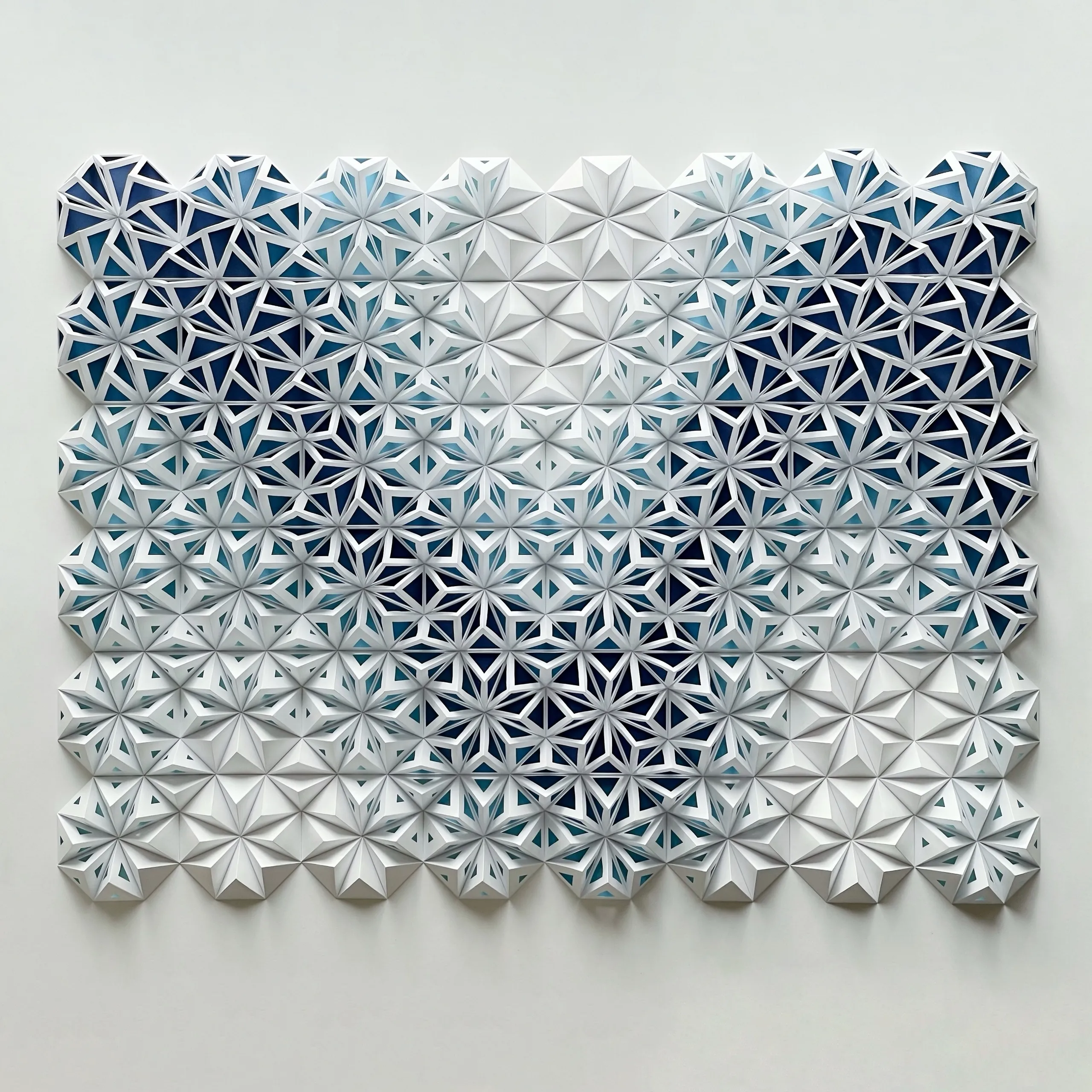 The whole work head-on, a field of white paper stars shading into deep blue towards the bottom