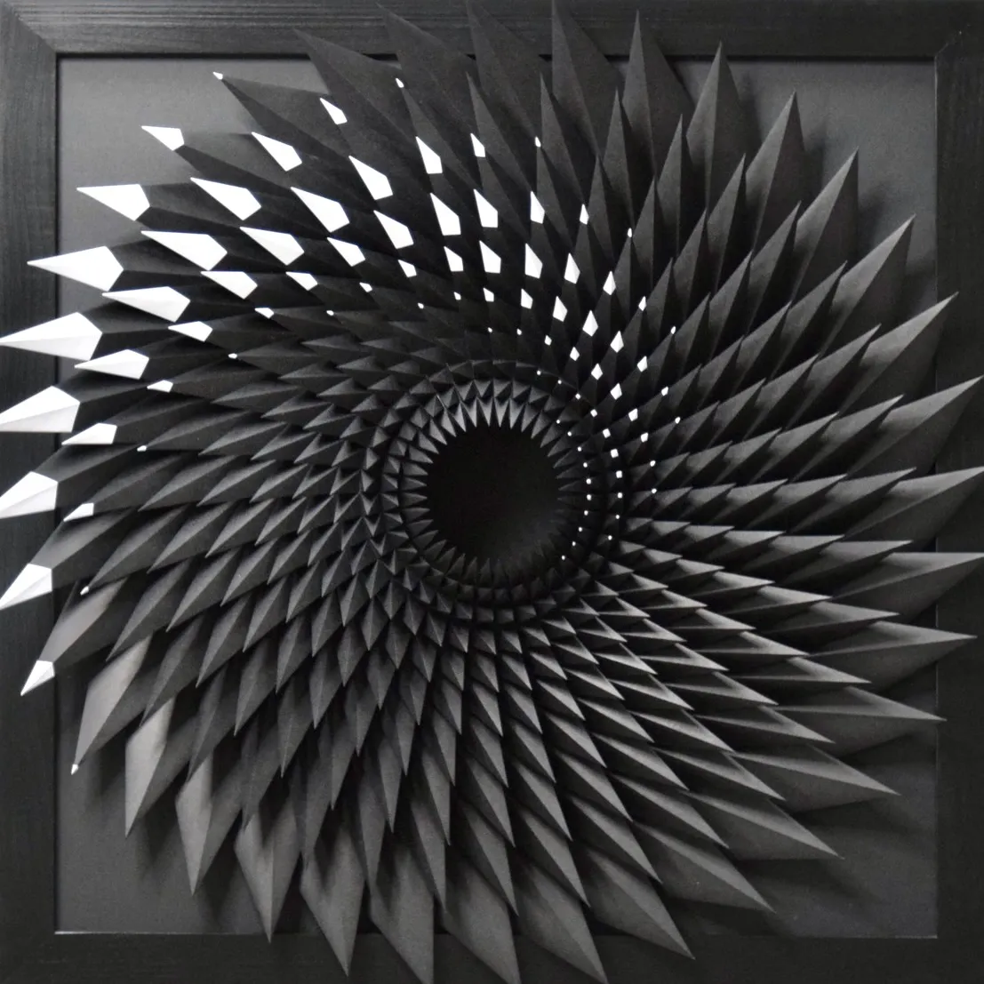 A black vortex of paper spikes in a black frame, a deep hole at its centre, single tips flashing white