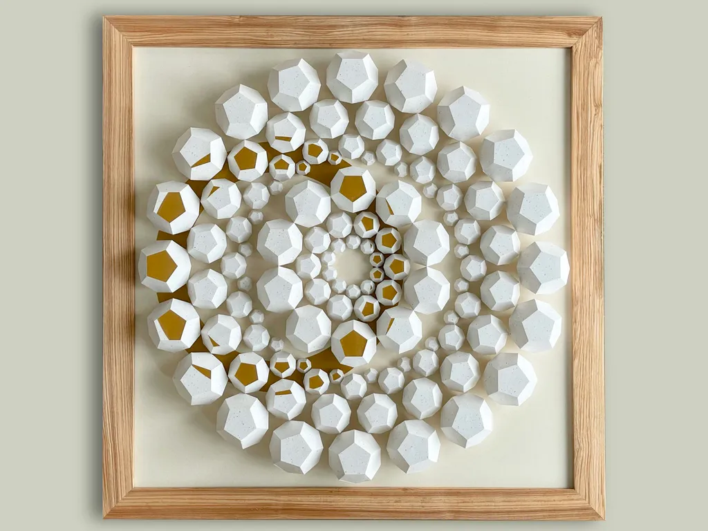 Big Art Show 2026 – The framed work “Exoresonance” on a pale wall, concentric rings of white polyhedra with single faces in gold