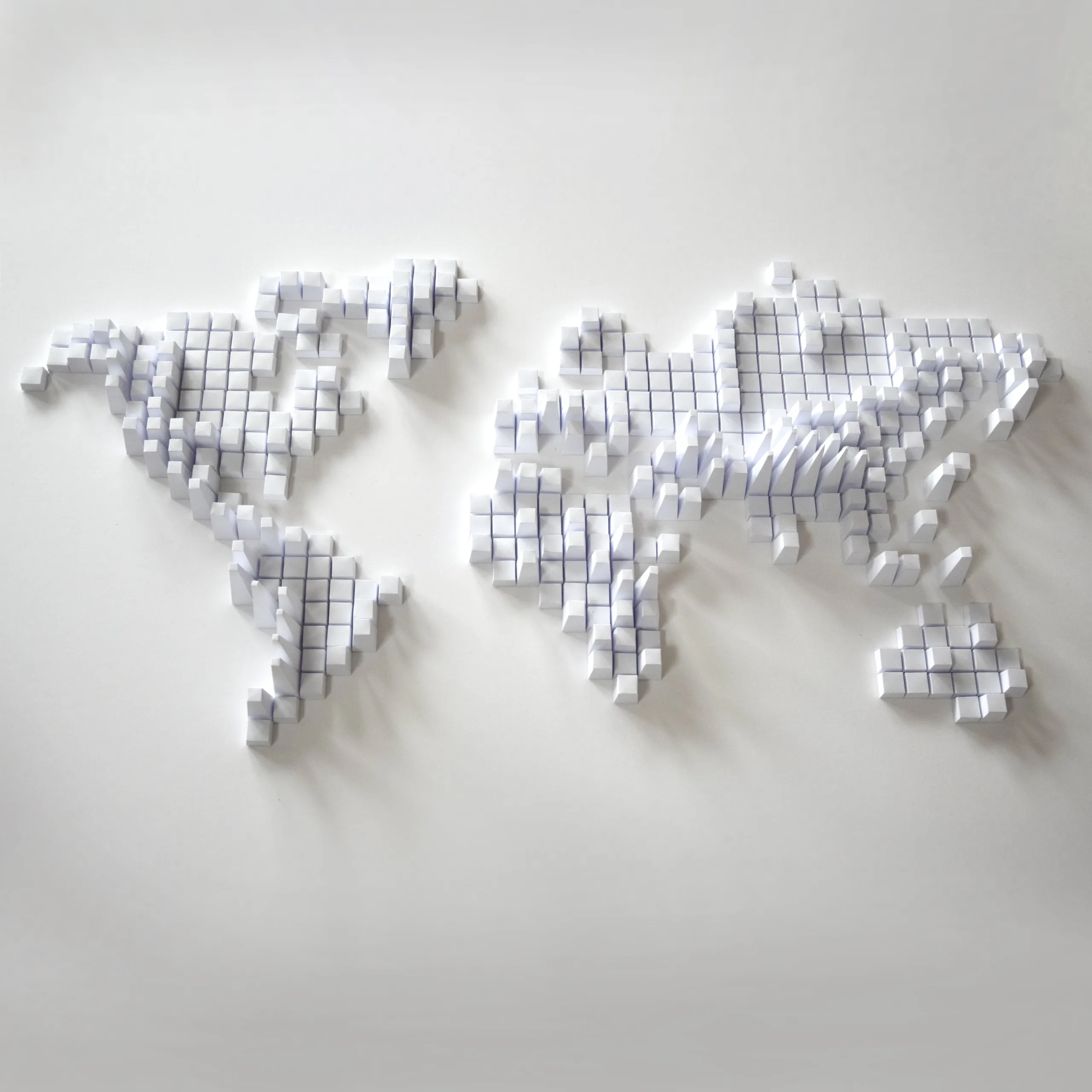 The white world map on a pale wall, its continents built up from thousands of small paper blocks