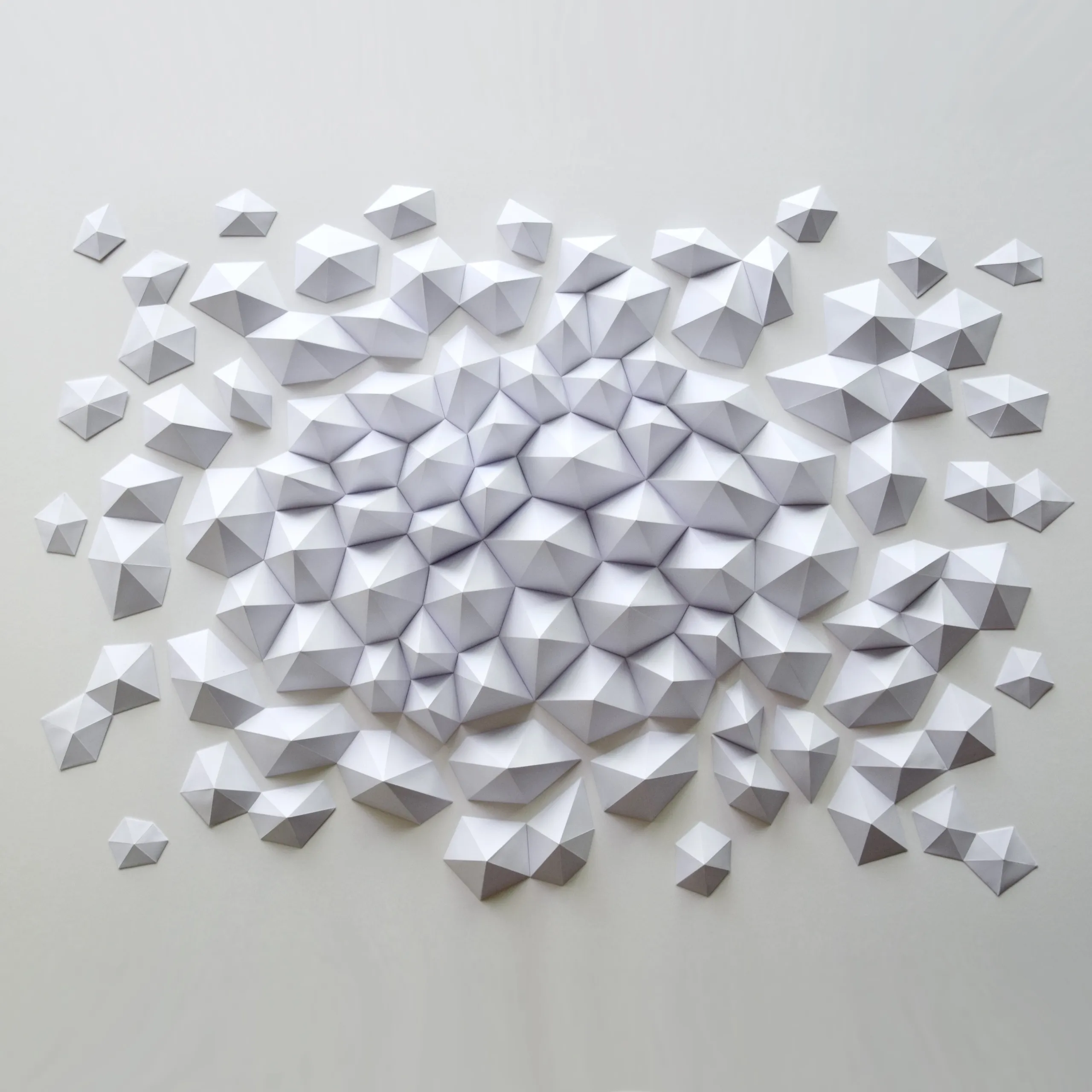 The whole work head-on, a hundred white paper shards massing at the centre and dissolving outwards