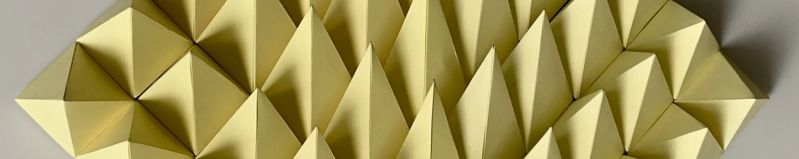 Yellow pyramids in dense ranks, the edge of the relief casting a hard shadow onto the wall at the right
