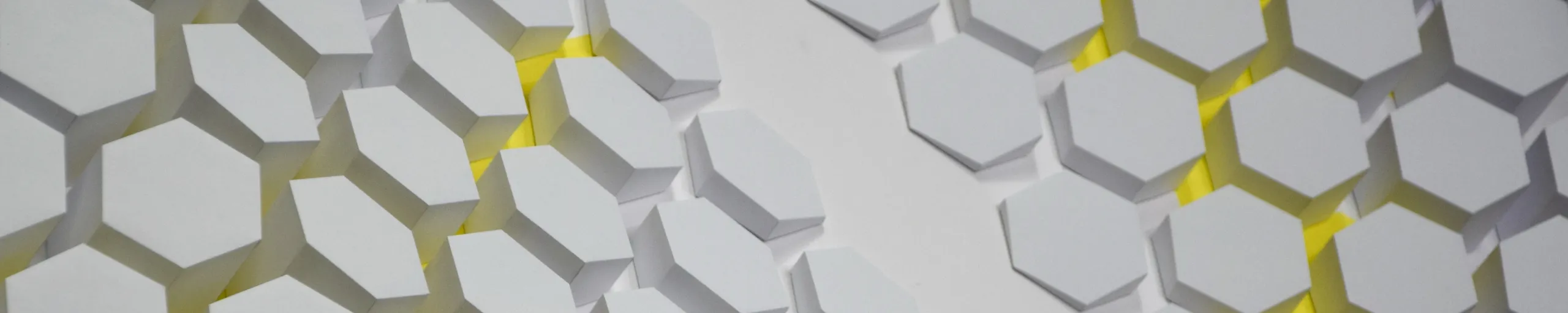 Across the honeycomb from a low angle, the yellow sitting as a narrow edge beneath each hexagon